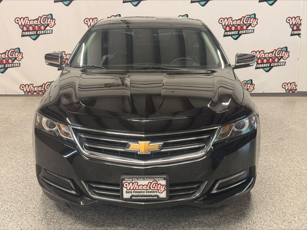Front view of a black Chevrolet SUV in a showroom with Wheel City Auto Finance Centers branding in the background.
