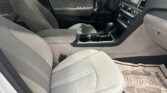 Interior of a car showing two front seats, light gray upholstery, and a center console with gear shifter and cupholders.