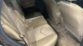 Beige fabric car interior; back seats with headrests, middle seatbelt, and door panel visible on left, front seats ahead.