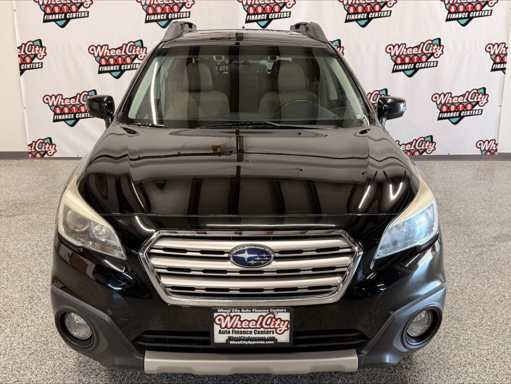 Front view of a black Subaru SUV in a showroom with Wheel City Auto Finance Centers banners in the background.
