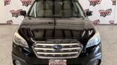 Front view of a black Subaru SUV in a showroom with Wheel City Auto Finance Centers banners in the background.