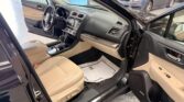 Open driver’s door shows beige leather interior and dashboard of a dark SUV inside a showroom.