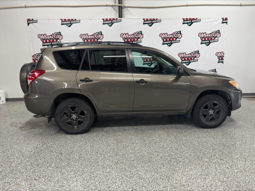Side view of a gray SUV in a showroom with a 'Wheel City Auto Finance Centers' banner in the background