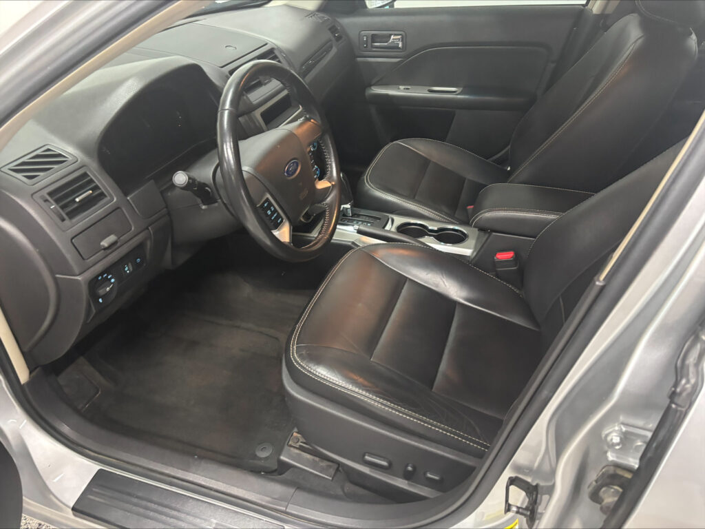Black leather driver and front passenger seats in a car with steering wheel and center console visible.