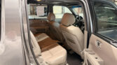 Interior of a beige-leather SUV with rear door open, showing front seats, center console, and passenger-side dashboard visible from the side.