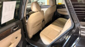 Open rear door showing tan leather car interior with two front seats and beige door panels inside a black SUV.