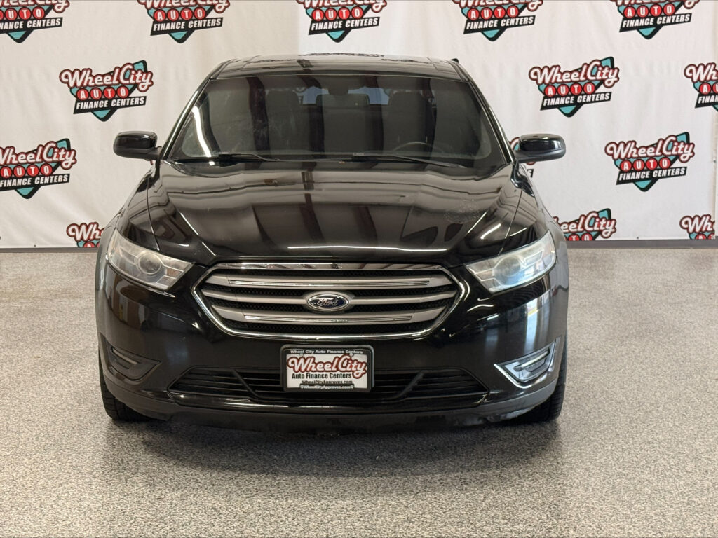 Front view of a black Ford SUV in a dealership showroom with Wheel City Auto Finance Centers banners in the background.