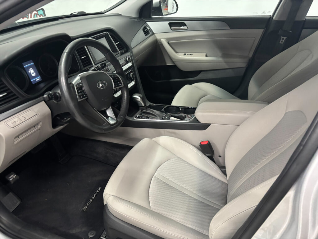 Interior of a modern car showing the driver and passenger seats, steering wheel, center console, and door panel from the passenger side view
