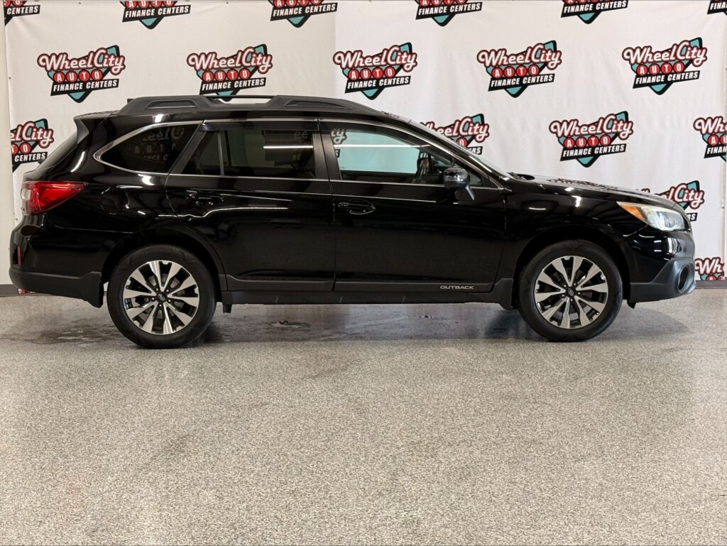 Side view of a black Subaru Outback SUV indoors, with a Wheel City Auto Finance Centers backdrop on the wall.