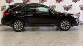 Side view of a black Subaru Outback SUV indoors, with a Wheel City Auto Finance Centers backdrop on the wall.