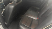 Rear passenger seating area of a car with black leather seats and white stitching, viewed from the doorway.