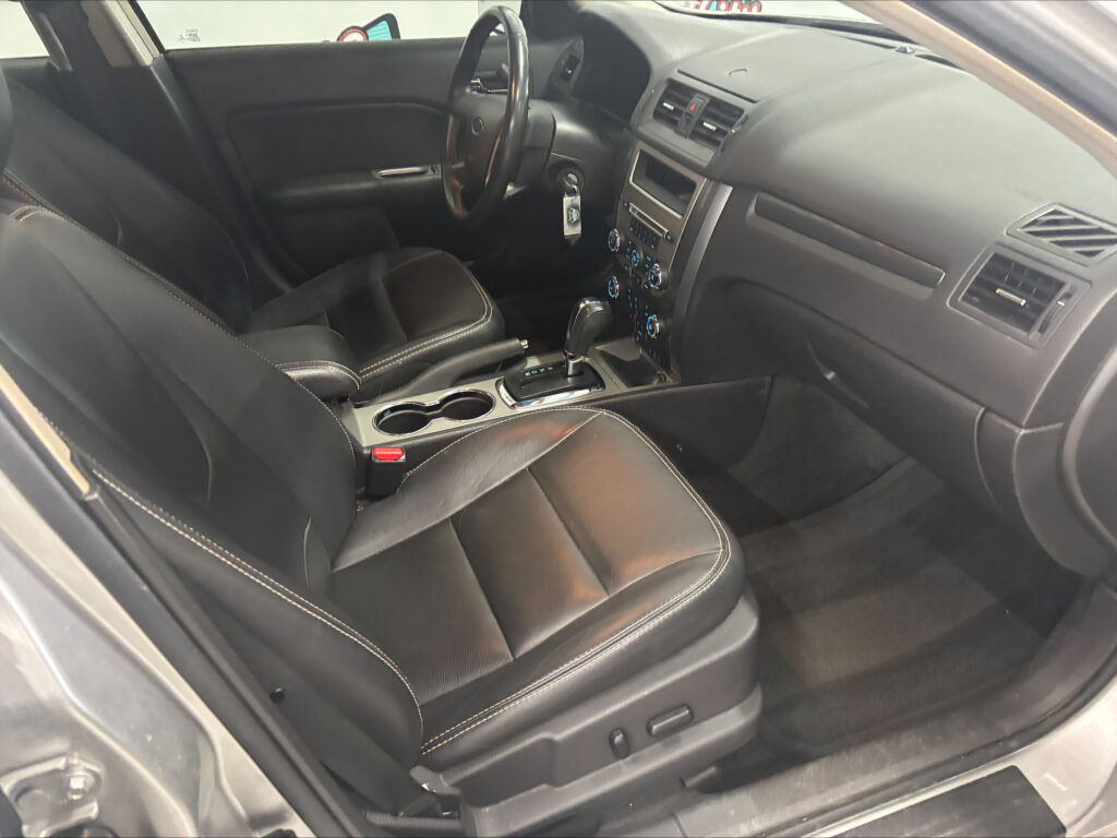 Interior of a dark leather car cabin with front seats, center console, and gear shifter visible at the center.