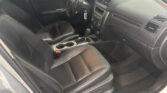 Interior of a dark leather car cabin with front seats, center console, and gear shifter visible at the center.