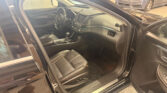 Interior of a dark leather car shown from the open driver’s side door with steering wheel and dashboard visible