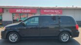 Front view of an auto shop with red storefront signs reading 'All Credit' and 'Wheel City Auto', a dark SUV parked in front.