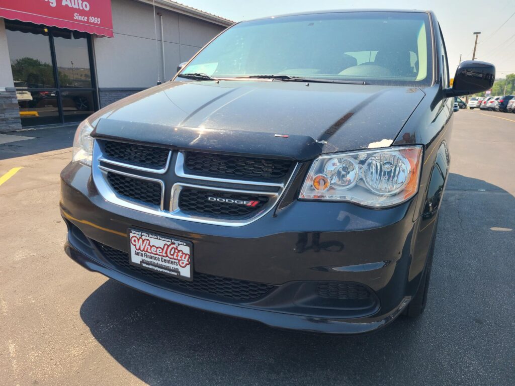 Front view of a black Dodge SUV parked at a dealership, showing the grille, headlights, and Wheel City license plate frame in the foreground.