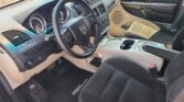 Front cabin of a Dodge Grand Caravan: steering wheel, beige dashboard, center console, and front seats with a floor mat reading 'Grand Caravan'.