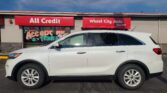 White SUV parked in front of a red storefront sign that reads 'All Credit Wheel City Auto'