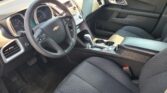 Interior of a Chevrolet sedan from the passenger side, showing the steering wheel, dashboard, center console, and front seats with black upholstery.