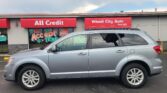 Silver SUV parked in front of a storefront with red signs reading 'All Credit' and 'Wheel City Auto'.