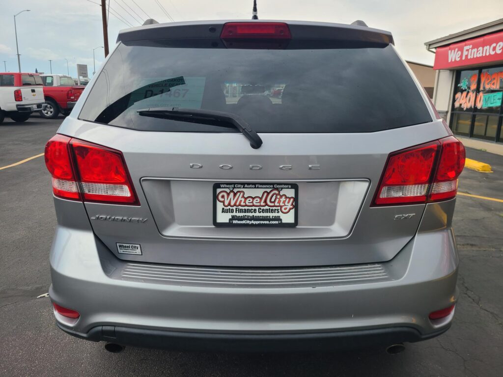 Rear view of a silver Dodge Journey SUV in a dealership lot, license plate frame reading Wheel City Auto Finance Centers.