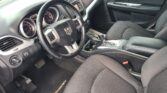Driver's-side interior of a dark SUV, showing steering wheel with Dodge emblem, instrument cluster, and center stack.