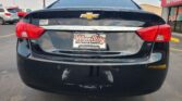 Rear of a black Chevrolet Impala with LT badge, showing Wheel City Auto Finance Centers license plate frame on a sunny parking lot.