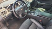 Front interior of a Chevrolet SUV: steering wheel with logo, dashboard, center console, and black leather seats.