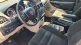 Front interior of a pickup/van cabin showing steering wheel, instrument cluster, center console, and passenger seat with dark fabric upholstery.