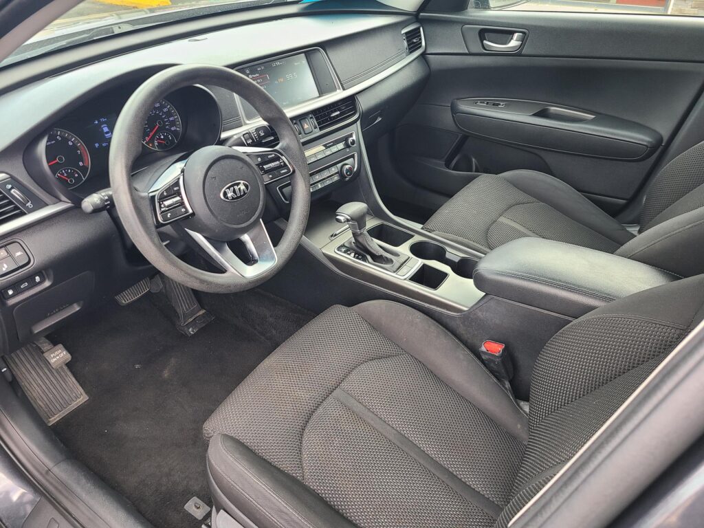 Interior of a modern car showing the driver's seat, steering wheel, center console, and front passenger seat.