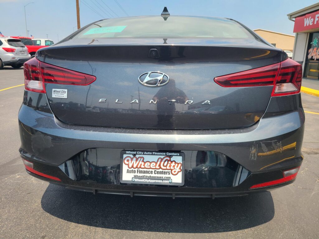 Rear view of a dark gray Hyundai Elantra in a parking lot, with a Wheel City license-frame visible on the bumper.