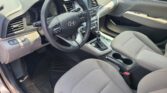 Interior of a car cabin showing the steering wheel, center console, gear shifter, and front seats viewed from the driver’s side.