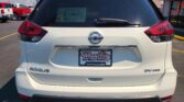 Rear view of a white Nissan Rogue SUV with Wheel City Auto Finance Centers dealer plate frame on the license plate area and a dusty rear window sticker.