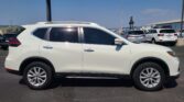 Side view of a white SUV parked in a lot with other cars and a building in the background, on a clear day.
