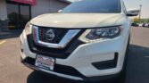 White Nissan SUV close-up at a dealership, Wheel City Auto Finance Centers sign visible in the background, front grille and logo in clear view.