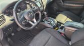 Interior of a modern car showing the driver's seat, steering wheel, center console, and front passenger seat with sunlit cabin details.