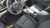Dark fabric car interior with steering wheel on the left, dashboard gauges, center console, and touchscreen display visible between the seats