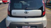 Rear view of a silver Kia Soul in a car dealership lot, with a Wheel City Auto Finance Centers license plate frame and dealer stickers on the rear window.