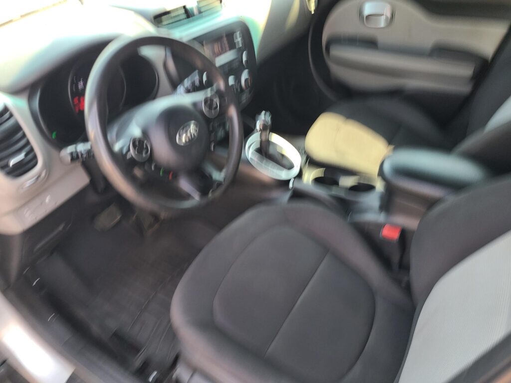 Blurry view of a car interior showing the steering wheel, center console, gear shifter, and front seats.