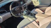 Interior of a car: beige seats, steering wheel, and center console with infotainment screen and controls visible.