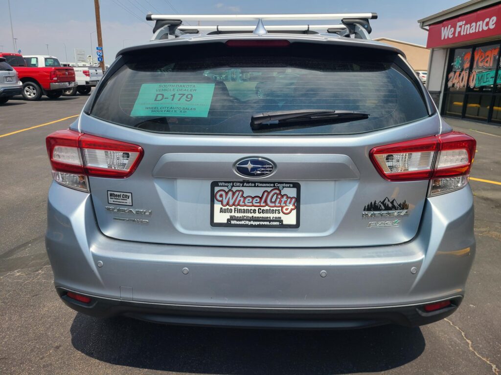 Rear view of a silver Subaru SUV with roof rack, dealership paper in rear window showing D-179 and Wheel City Auto Finance Centers.