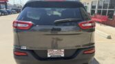 Rear view of a dark gray Jeep SUV parked in a dealership lot; visible Wheel City license plate frame on the bumper and a rear windshield wiper.