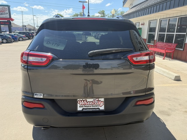 Rear view of a dark gray Jeep SUV parked in a dealership lot; visible Wheel City license plate frame on the bumper and a rear windshield wiper.