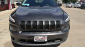 Front view of a dark gray Jeep SUV parked in a dealership lot, featuring a seven-slot grille and Wheel City license plate frame on the front bumper.