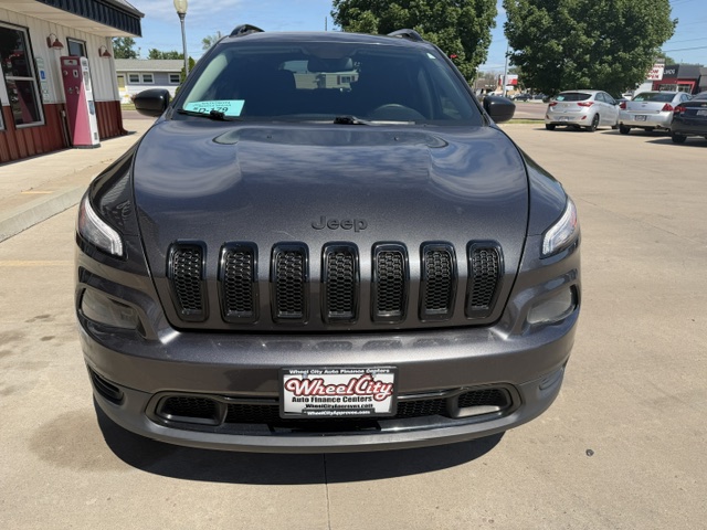 Front view of a dark gray Jeep SUV parked in a dealership lot, featuring a seven-slot grille and Wheel City license plate frame on the front bumper.