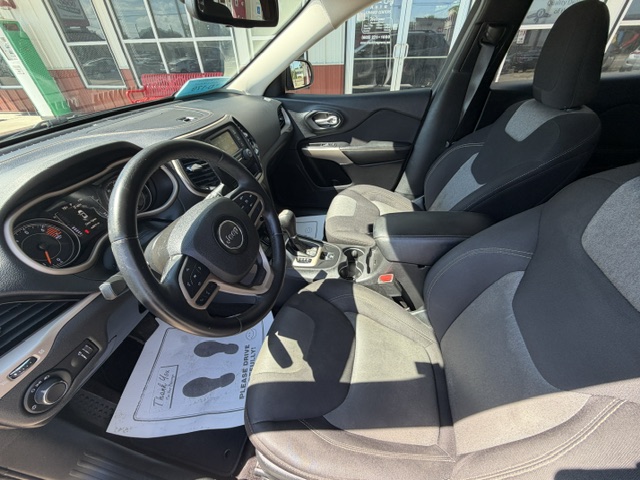 Interior of a Jeep showing the steering wheel, driver's seat, center console with gear shifter, and front passenger seat in a sunlit car