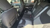 Interior of a car showing black and gray cloth seats, front bucket seats, and a three-seat rear bench with seatbelts visible