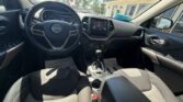 Front interior of a Jeep: steering wheel with Jeep logo, center touchscreen, climate controls, gear shifter, and front seats, view from the driver’s seat.