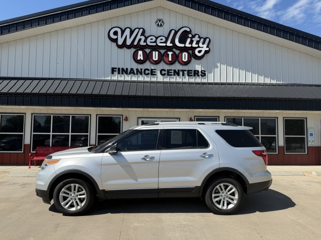 White SUV parked in front of the Wheel City Auto Finance Centers storefront with its sign visible.