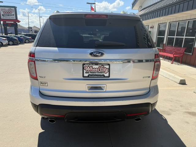 Rear of a white Ford SUV with XLT badge, parked in a dealership lot; Wheel City license plate frame.
